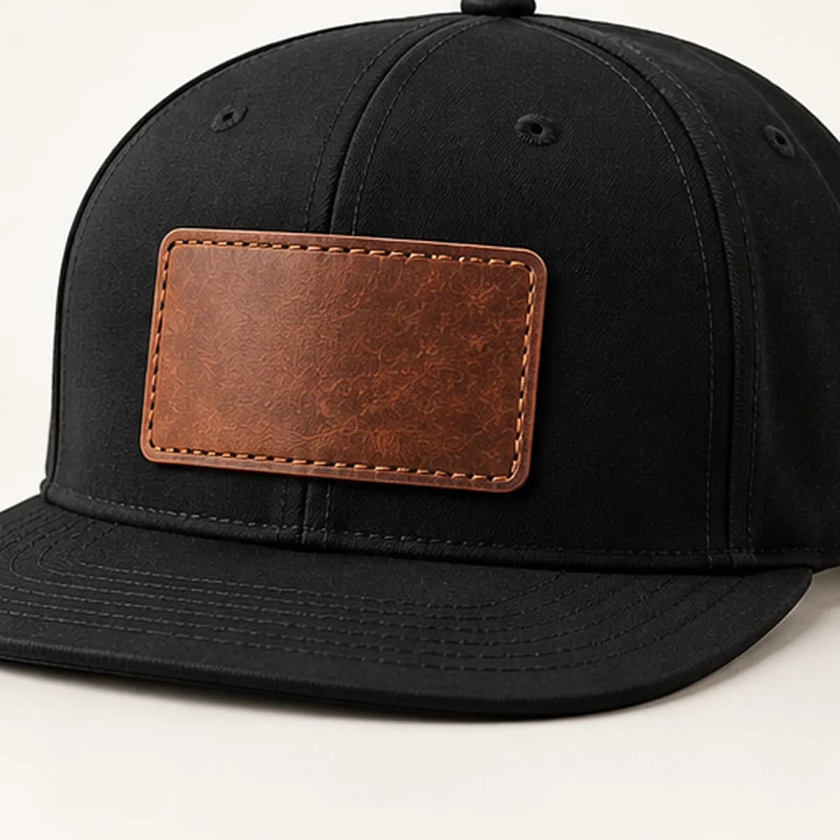 A black flat-peak cap with an engraved leather patch
